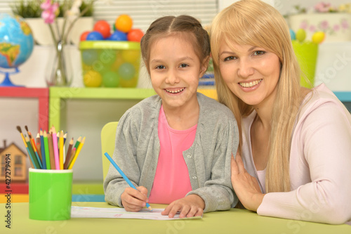 little cute girl with mother drawing  at home