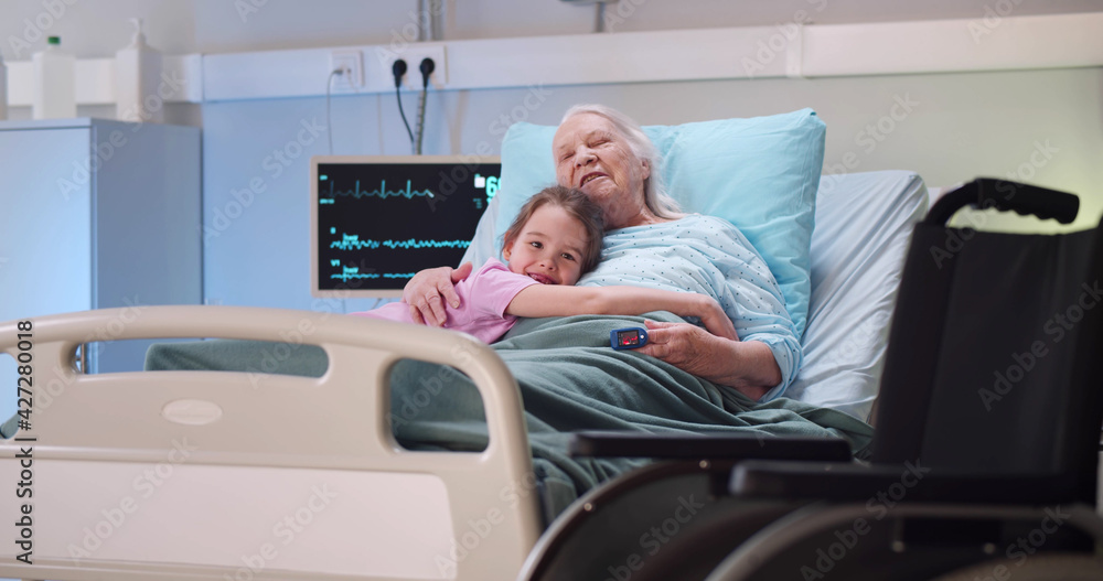 Granddaughter visiting and embracing disabled grandmother in hospital Granddaughter visiting and embracing disabled grandmother in hospital