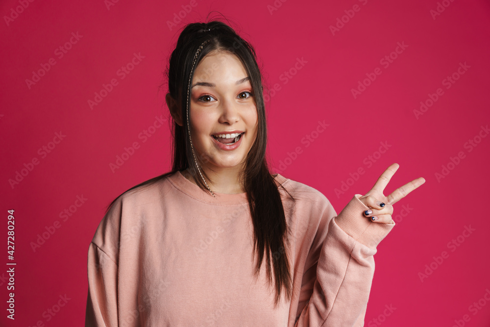Asian brunette woman smiling and gesturing peace sign Asian brunette woman smiling and gesturing peace sign