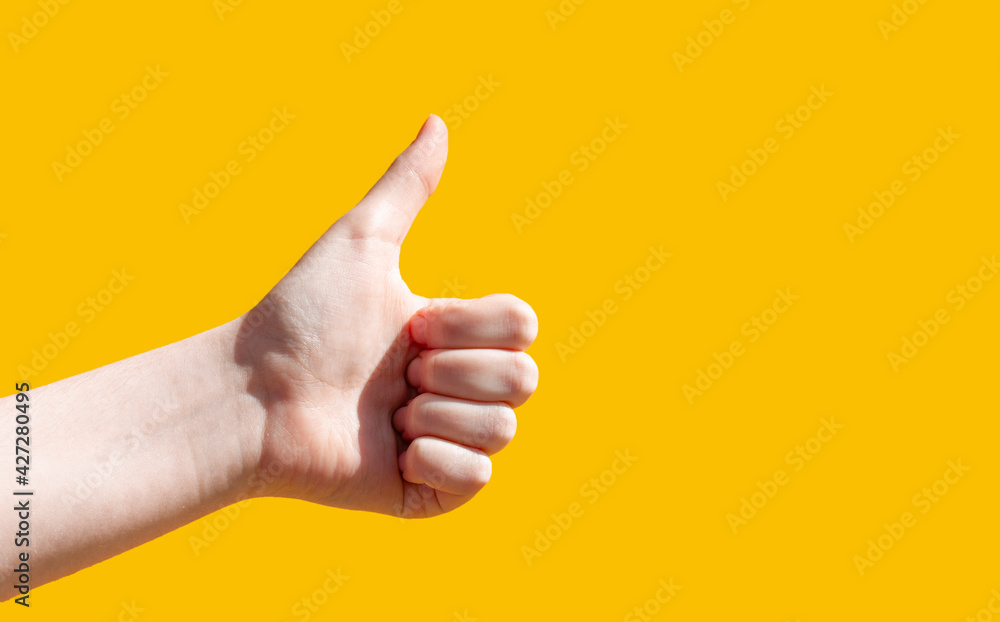 Close-up on a yellow background, the hand shows a thumbs up. Like it