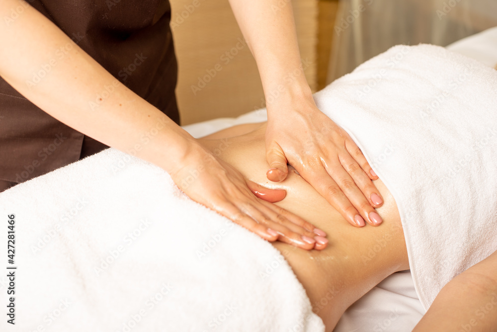 Close up hands of chiropractor or masseur making relaxing massage of stomach for lying woman in clinic interior. Professional woman doctor masseur during work with patient Close up hands of chiropractor or masseur making relaxing massage of stomach for lying woman in clinic interior. Professional woman doctor masseur during work with patient