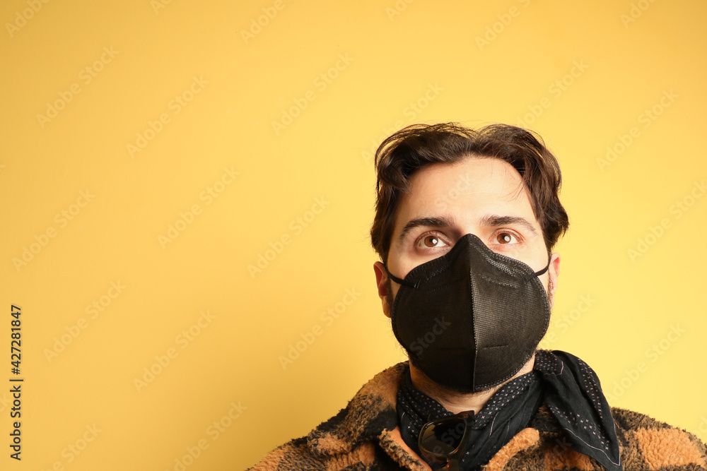 Portrait of man wearing black medical mask. Over yellow background. Portrait of man wearing black medical mask. Over yellow background.