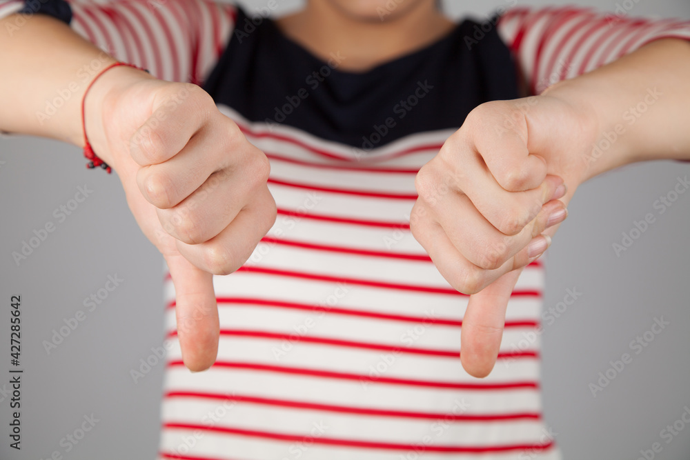 Young woman shows a sign of a thumb down. Negative gesture.