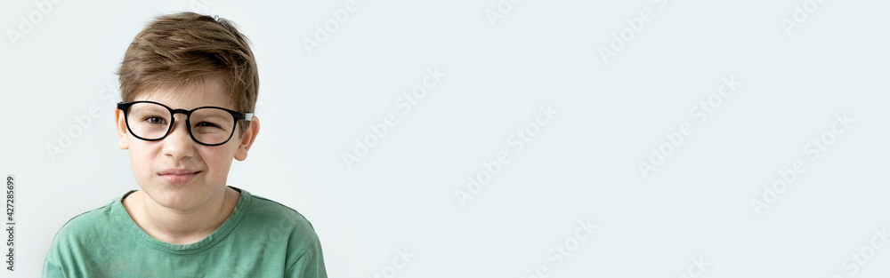 Smiling cute surprised boy in a green T-shirt and glasses. Copy space. Schoolboy 