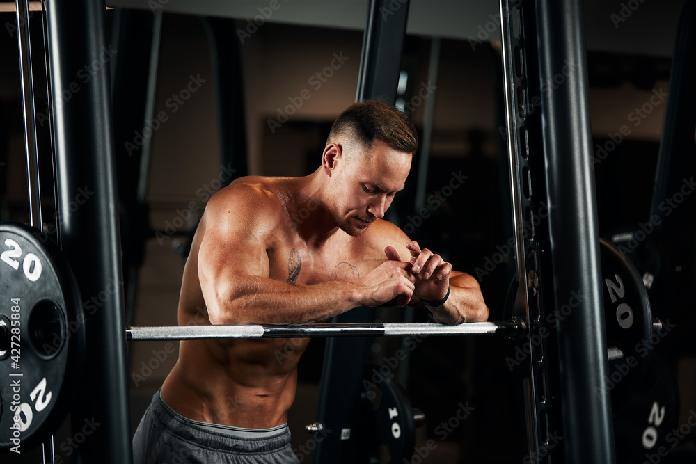 Closeup portrait of a muscular man workout with barbell at gym. Brutal bodybuilder athletic man with six pack, perfect abs, shoulders, biceps, triceps and chest Closeup portrait of a muscular man workout with barbell at gym. Brutal bodybuilder athletic man with six pack, perfect abs, shoulders, biceps, triceps and chest