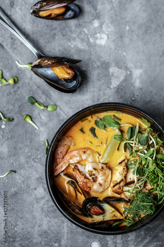 Thai Tom Yam spicy soup with seafood , popular Thai cuisine. On grey clay background with mussels