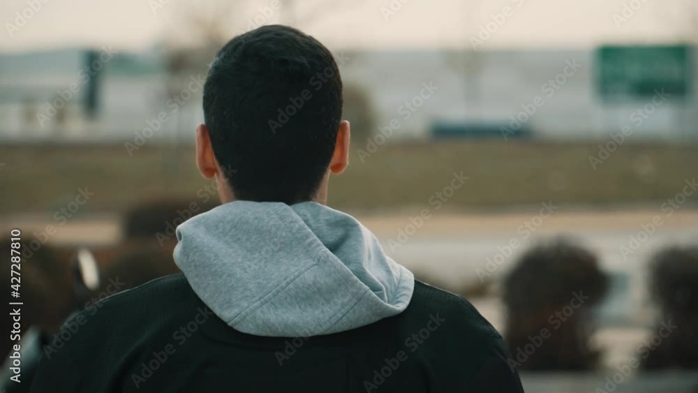 Hombre con chaqueta negra y capucha gris caminando de espaldas , hombre de cabello negro caminando hacia su motocicleta Hombre con chaqueta negra y capucha gris caminando de espaldas , hombre de cabello negro caminando hacia su motocicleta