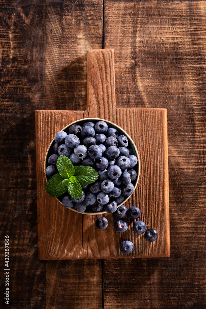 Bowl of fresh blueberries on rustic wooden board. Organic food blueberries and mint leaf for healthy lifestyle. Bowl of fresh blueberries on rustic wooden board. Organic food blueberries and mint leaf for healthy lifestyle.