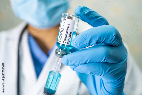 Doctor holding syringe with vaccine development medical for doctor use to treat illness patients Covid-19 coronavirus vaccine at hospital.