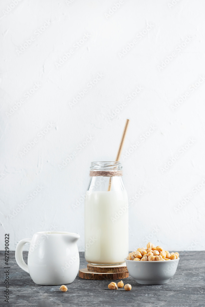Vegan and Vegetarian Plant-Based Milk Made from Raw Chickpeas in a Glass Bottle with Eco Friendly Paper Straws with White Cream Jar Vegan and Vegetarian Plant-Based Milk Made from Raw Chickpeas in a Glass Bottle with Eco Friendly Paper Straws with White Cream Jar