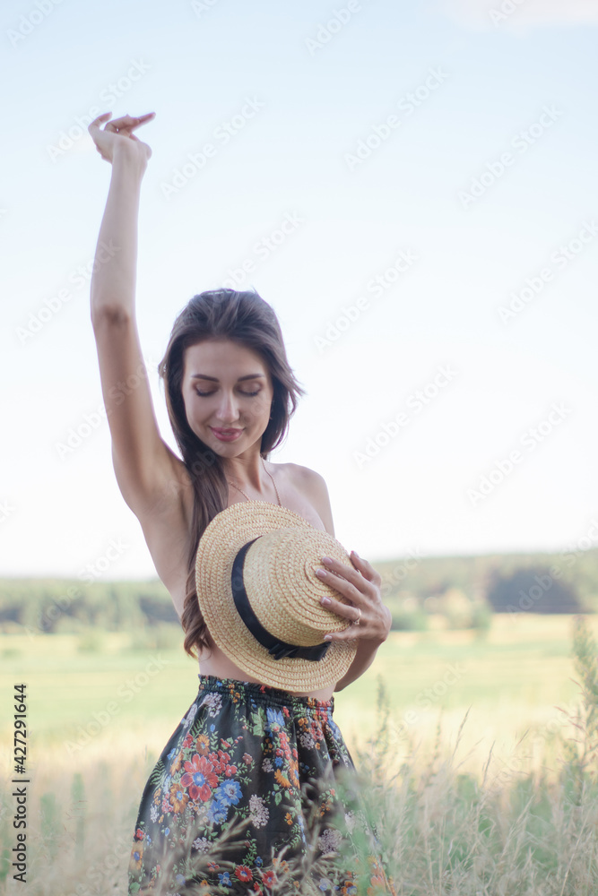 topless brunette woman covering her breasts with straw hat in the field topless brunette woman covering her breasts with straw hat in the field