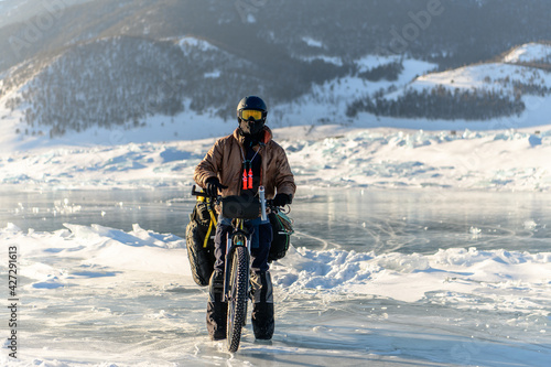 Bicyclist on the coast of Baikal lake in winter. Buguldeika, Irkutsk Region, Russia