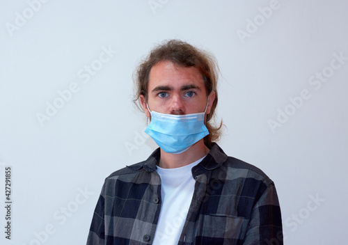 A side view of a Spanish young bearded male wearing a protective facemask incorrectly