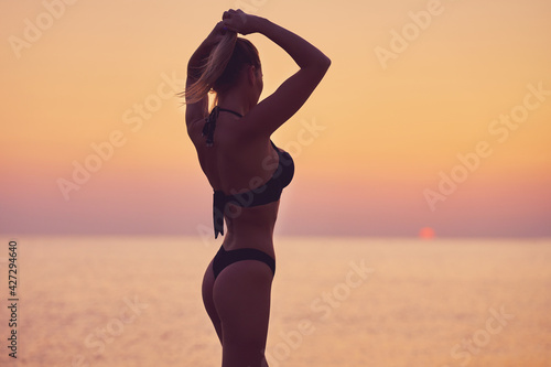 Silhouette of sexy woman posing at sunrise at the beach © Kalim
