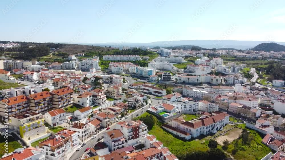 Aerial pan view in Portugal of buildings with red roofs, green trees, and wavy coastline, drone 4k shot Aerial pan view in Portugal of buildings with red roofs, green trees, and wavy coastline, drone 4k shot