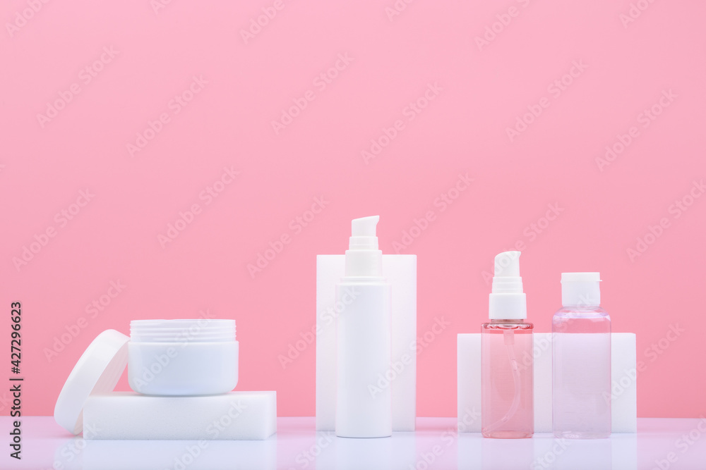 Set of beauty products for skin care in white tubes on white table against bright pink background with copy space. Concept of skin daily, anti aging or anti acne treatment Set of beauty products for skin care in white tubes on white table against bright pink background with copy space. Concept of skin daily, anti aging or anti acne treatment