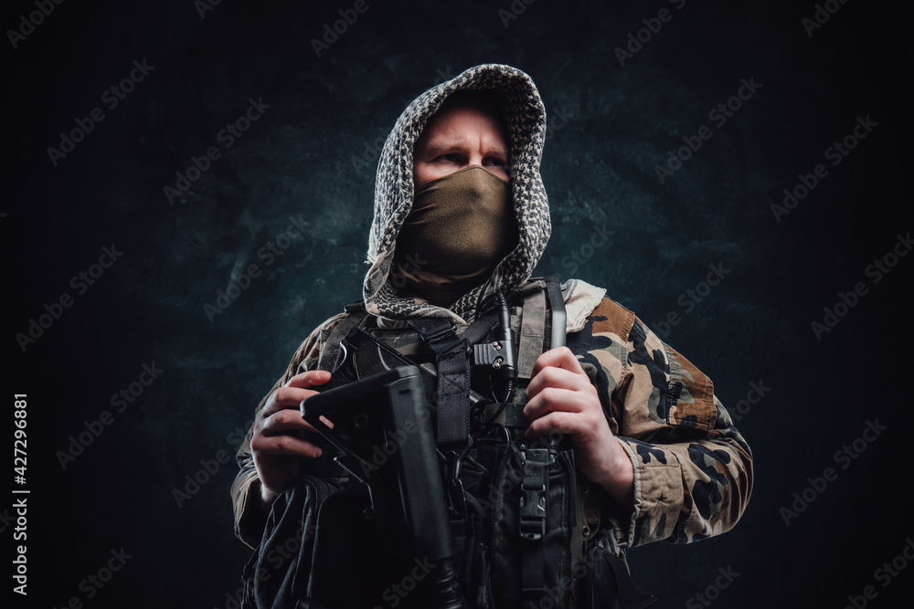 Fototapeta premium Modern army agent in camouflage clothing with a hood and rifle