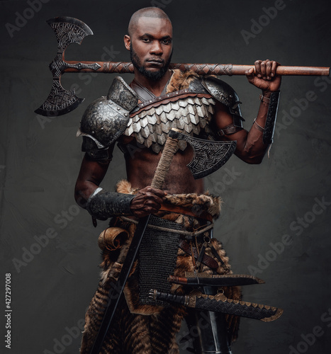 Black skinned antique soldier with dual axes looking at camera