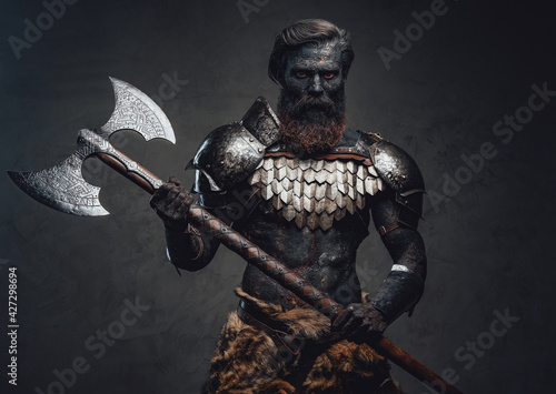 Evil soldier with scorched skin standing and holding his axe
