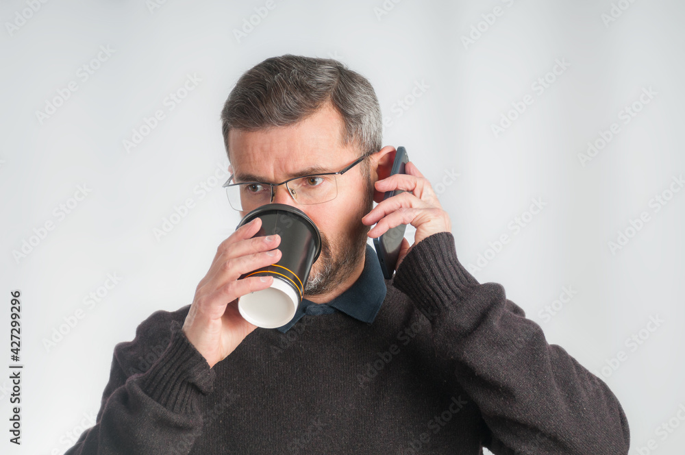 Adult man with mobile phone drinking from disposable cup Adult man with mobile phone drinking from disposable cup