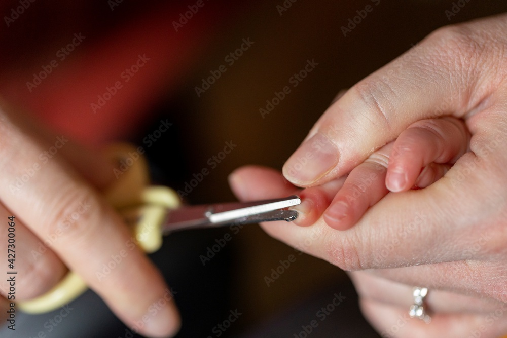 A close up portrait of a mother clipping the nails of a small baby hand. The childs fingernails are being cut by a special type of scissors instead of a nail clipper because they were long and sharp. A close up portrait of a mother clipping the nails of a small baby hand. The childs fingernails are being cut by a special type of scissors instead of a nail clipper because they were long and sharp.