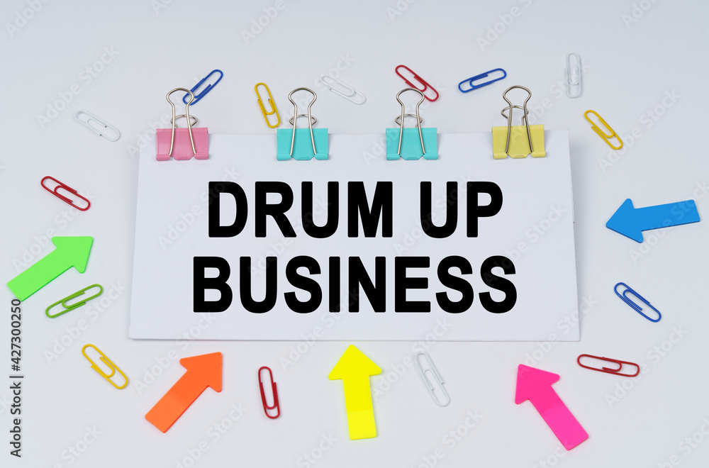 On the table there are paper clips and directional arrows, a sign that says - Drum Up Business On the table there are paper clips and directional arrows, a sign that says - Drum Up Business