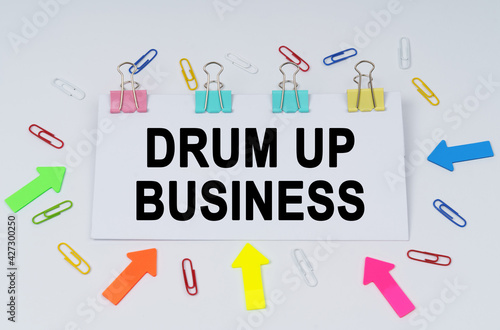 On the table there are paper clips and directional arrows, a sign that says - Drum Up Business