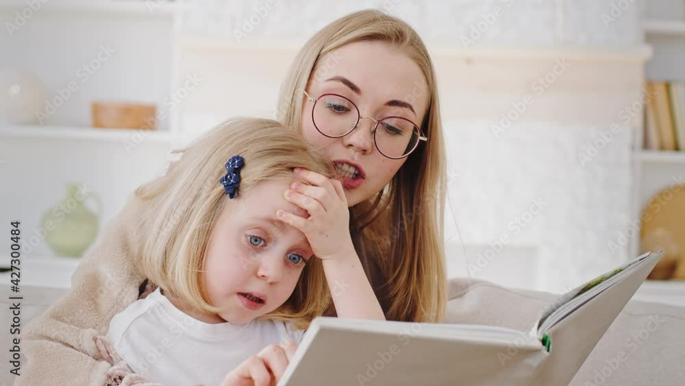 Portrait caucasian mother in glasses reads book fairy tale to child little daughter teaches baby at home, close-up reading story mom spends time with kid, concept of preschool education and childcare Portrait caucasian mother in glasses reads book fairy tale to child little daughter teaches baby at home, close-up reading story mom spends time with kid, concept of preschool education and childcare
