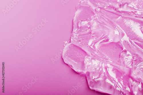 Transparent liquid gel on a pink background with free space.