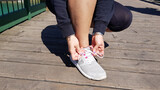 Young athlete woman tying running shoes in the park outdoor