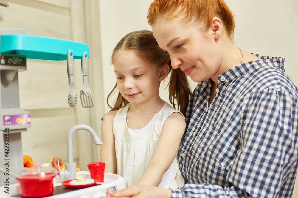 a caring mother plays with her daughter, teaches her the profession of a cook. the girl is very interested in how to cook properly. a caring mother plays with her daughter, teaches her the profession of a cook. the girl is very interested in how to cook properly.