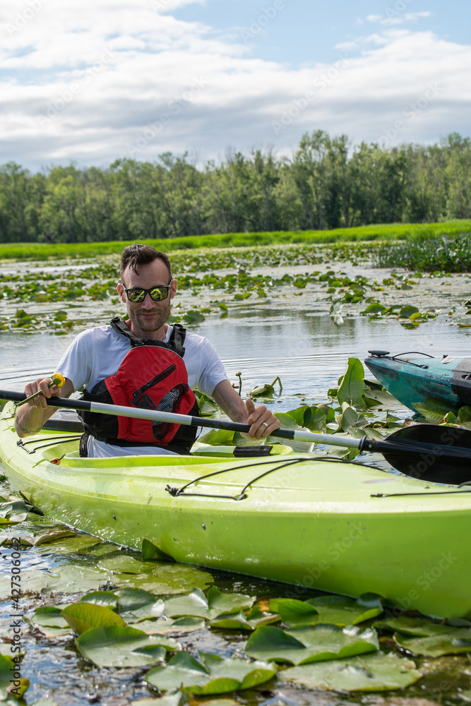 Young man kayaking on lily pads in the Canadian wilderness