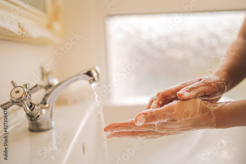 A close up shot of a woman washing hands with soap and warm water at home to prevent infection of corovavirus. Concept of hygiene. photo