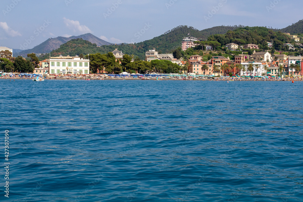 Seascape with azure water in the foreground and Italian port city in the background