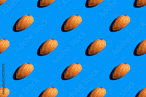 Background from almonds. Trendy sunny pattern of almonds on a bright blue background. Colorful pattern. View from above