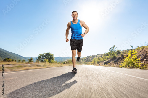 Full length portrait of a young man jogging on an asphalt road