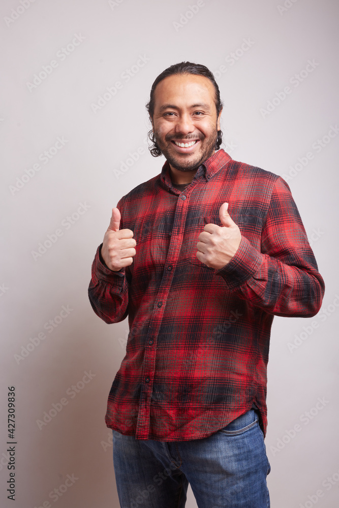 young Hispanic man with beard in his 30s celebrating with his thumbs up and smiling on white background young Hispanic man with beard in his 30s celebrating with his thumbs up and smiling on white background