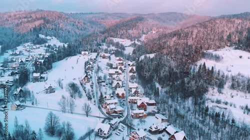 Zakopane, Poland. Arial view of a little town with small houses in a mountain landscape. Street, Houses, and trees, covered in snow with blue sky in the background.  photo