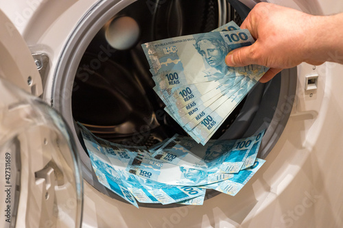 Brazilian money, the concept of money laundering from illegal activities. The man puts a large amount of banknotes into the washing machine