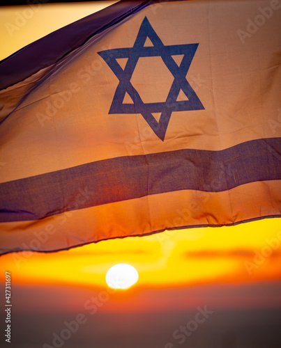 Israel flag with sky at sunset in the background
