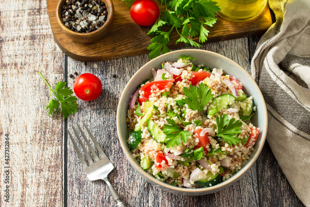 Food dieting concept, tuna salad. Couscous salad with conserved tuna, tomatoes, cucumbers and purple onions on rustic wooden table. Copy space. Food dieting concept, tuna salad. Couscous salad with conserved tuna, tomatoes, cucumbers and purple onions on rustic wooden table. Copy space.