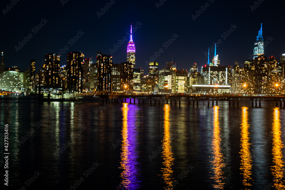 The lights of Midtown Manhattan reflected in the East River at night.