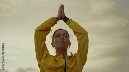 Focused girl doing yoga tree pose. Attractive woman holding hands above head