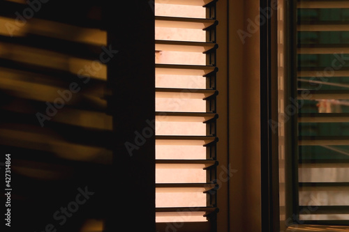 Window with shutters, illuminated by warm golden hour light. Selective focus.