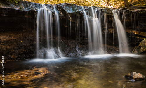 colorful autumn foliage with calming cascading waterfall in Pennsylvania.