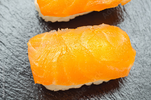 Closeup of smoked salmon nigiri prepared by a Japanese chef in a restaurant