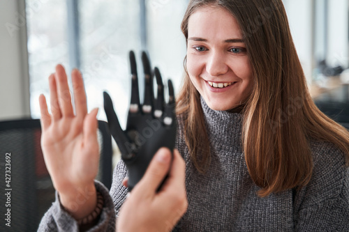Fototapeta Woman comparing her hand with bionic prosthesis limb while sitting
