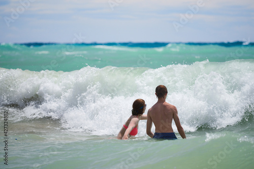 Młodzież aktywnie wypoczywająca w słoneczny letni dzień nad ciepłym morzem, kąpiele morskie wśród fal.