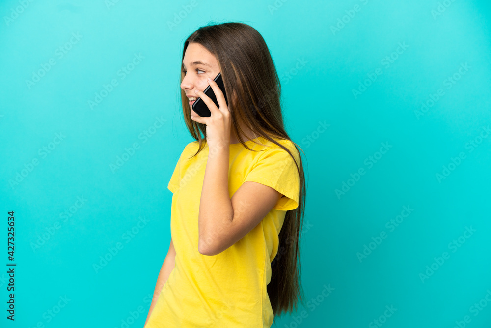 Little girl over isolated blue background keeping a conversation with the mobile phone with someone Little girl over isolated blue background keeping a conversation with the mobile phone with someone