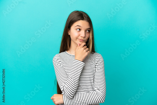 Little girl over isolated blue background thinking an idea while looking up